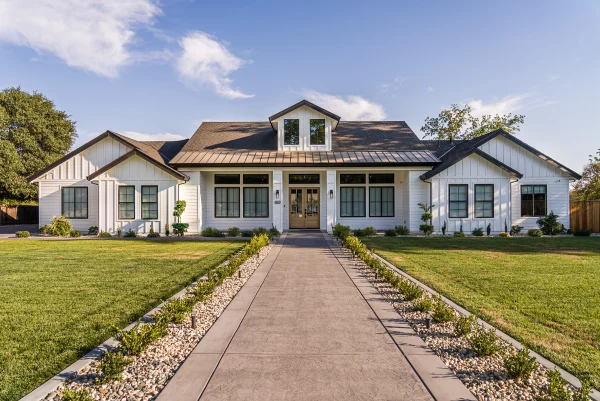 White farmhouse with a long front walkway and lawn