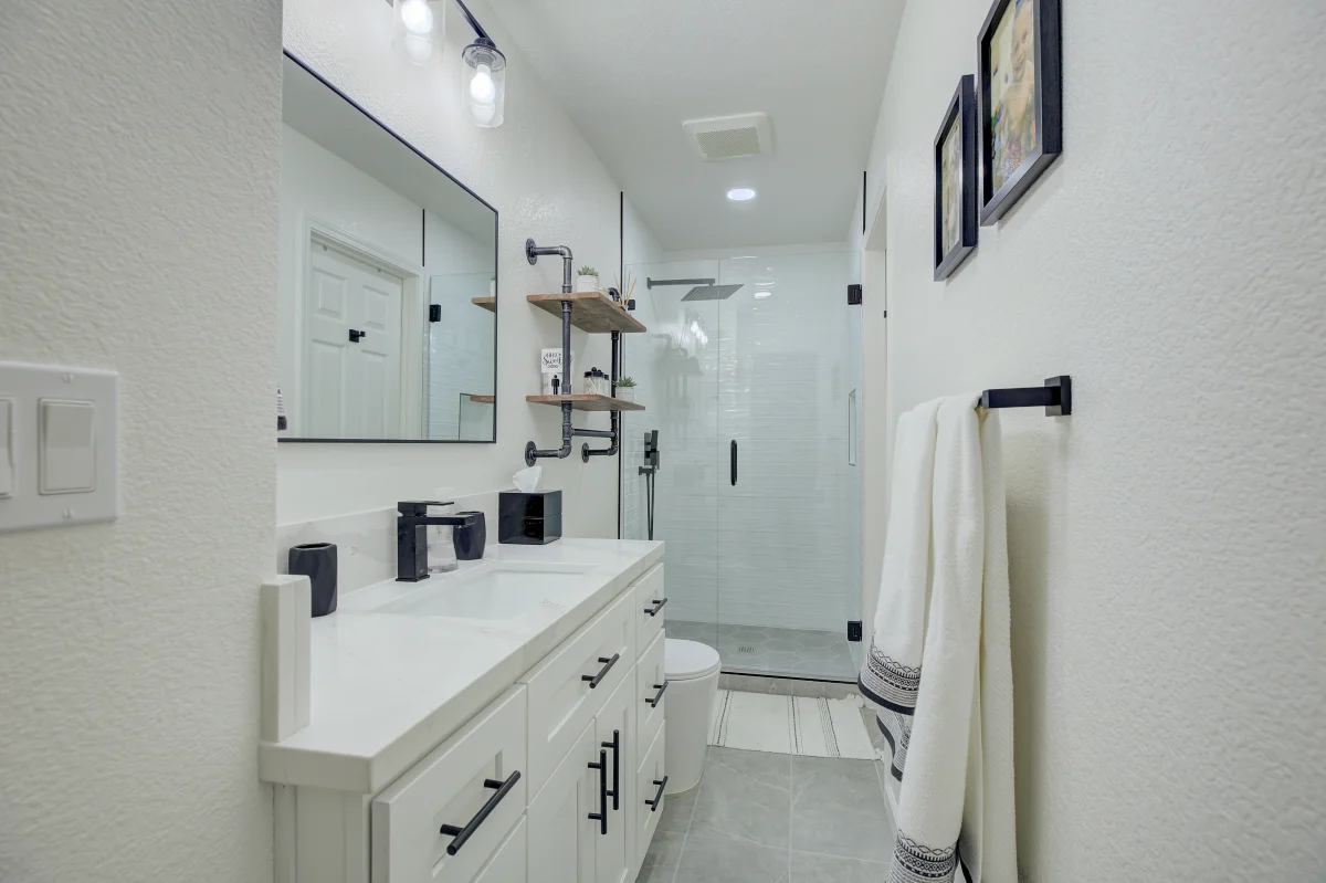 Bathroom with a white vanity, black fixtures and a glass shower
