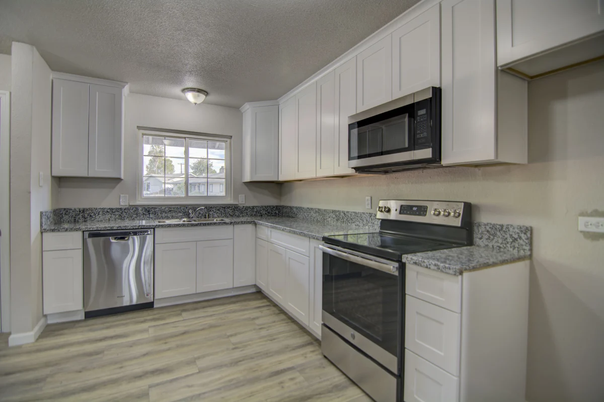 L-shaped kitchen with white cabinets, granite counters and stainless appliances