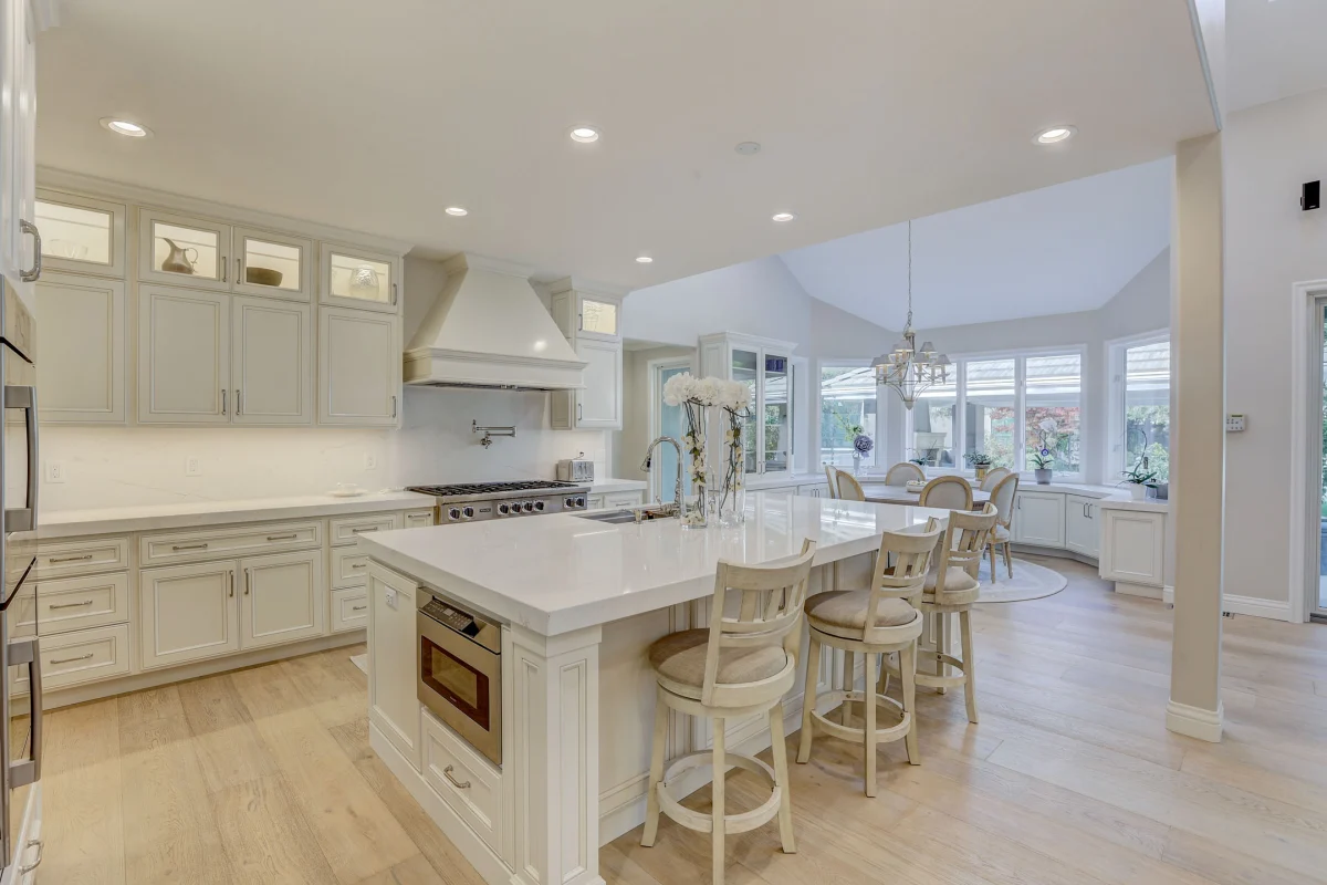 White kitchen with an island, glass-front cabinets and a vaulted ceiling