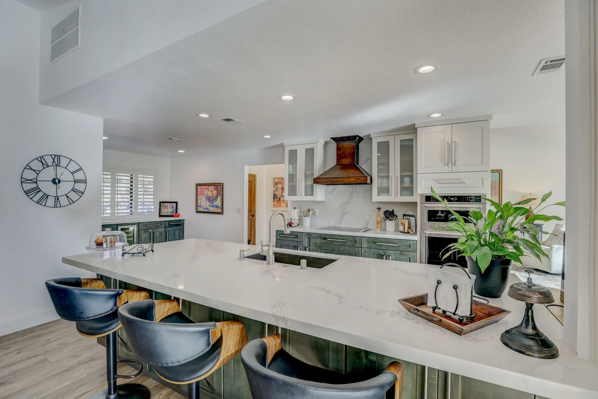 Kitchen with a large white island and blue counter stools