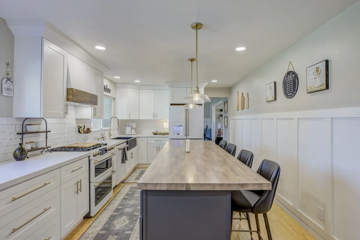 Long white kitchen with a wood-topped island and a navy base