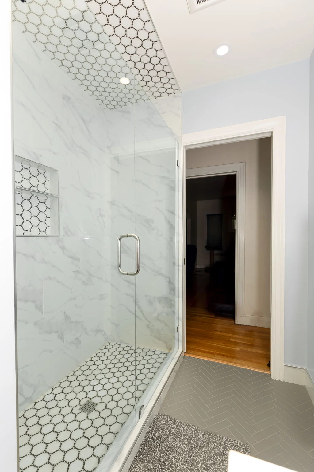 Glass shower with marble-look tile and a hexagon tile floor