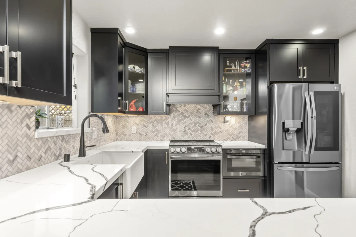 Kitchen with black cabinets, a white quartz counter and a herringbone backsplash