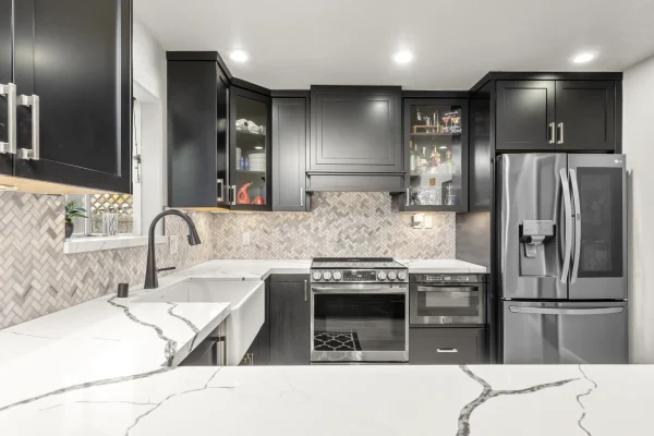 Kitchen with black cabinets, a white quartz counter and a herringbone backsplash