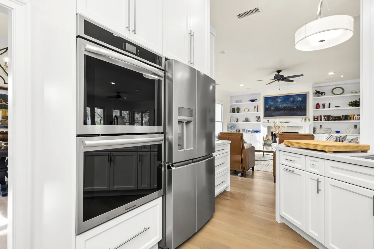 White kitchen with wall ovens and a stainless fridge