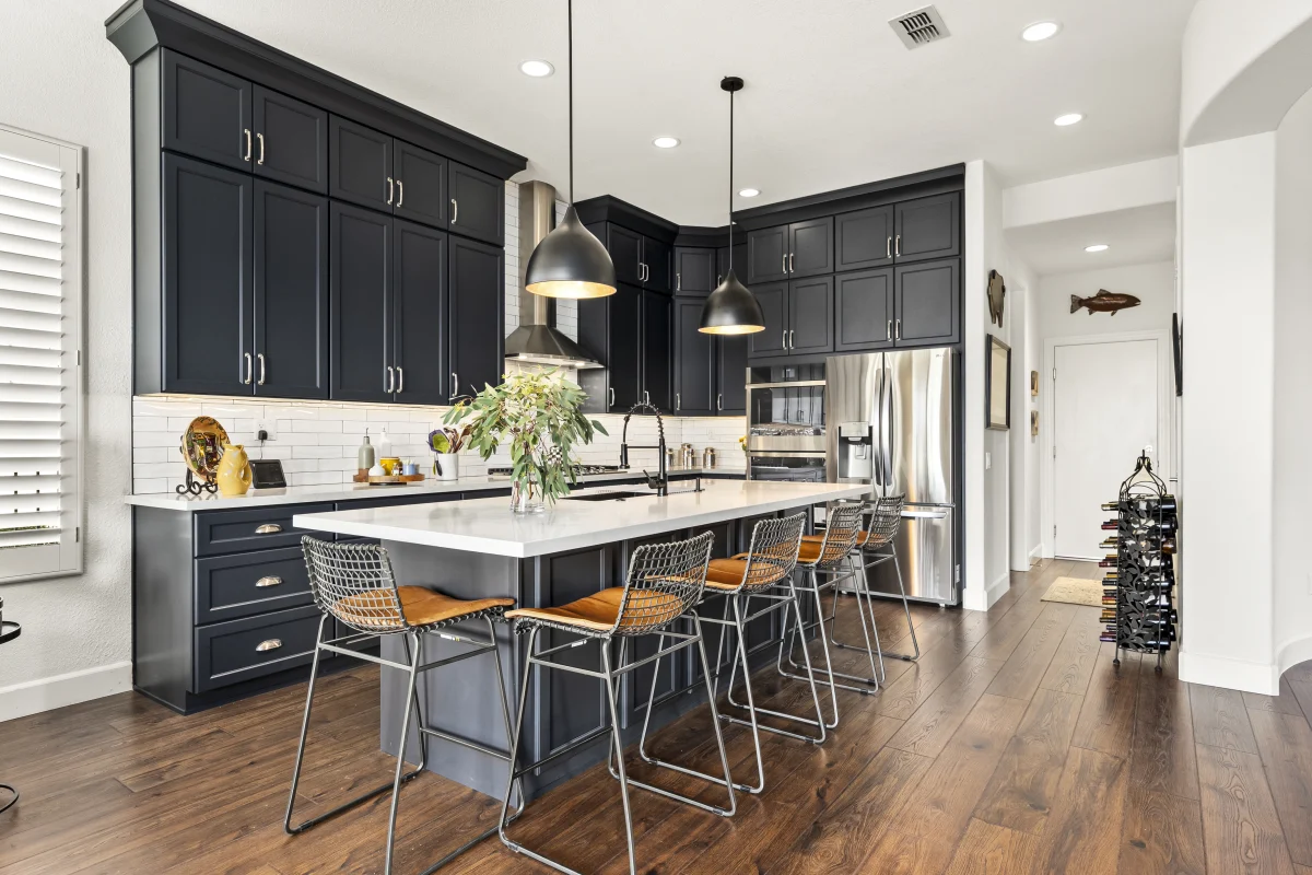 Kitchen with navy cabinets, a long island and pendant lights
