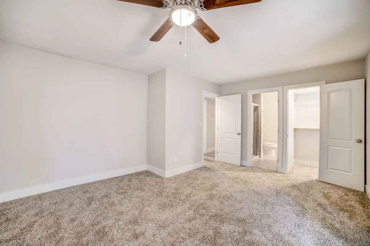 Empty bedroom with carpet and a ceiling fan