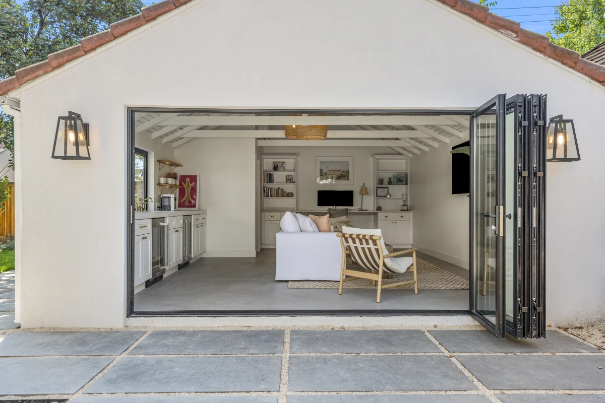 Converted garage with a glass folding door open to the driveway