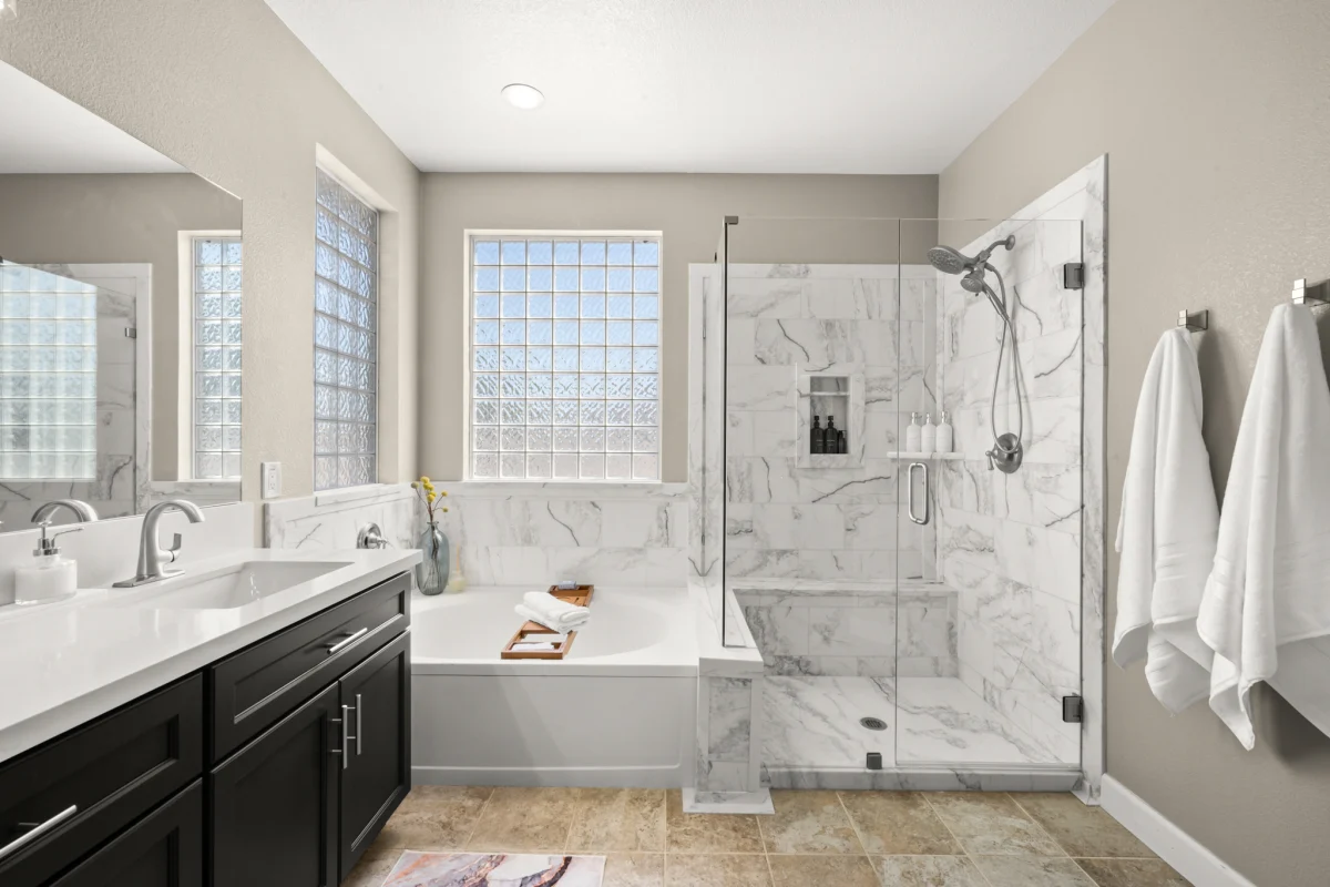 Bathroom with a dark vanity, tub and glass shower
