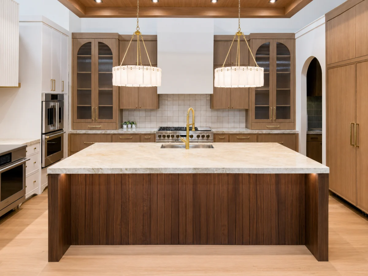 Kitchen with a walnut island, light stone countertop and two pendant lights