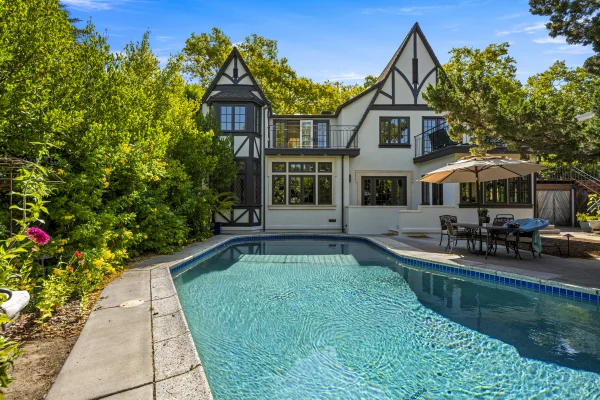 Tudor-style house with a pool and patio in the backyard