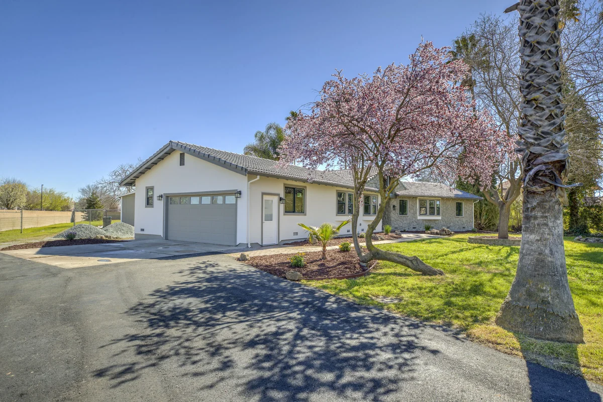 Single-story house with a gray garage door and a flowering tree