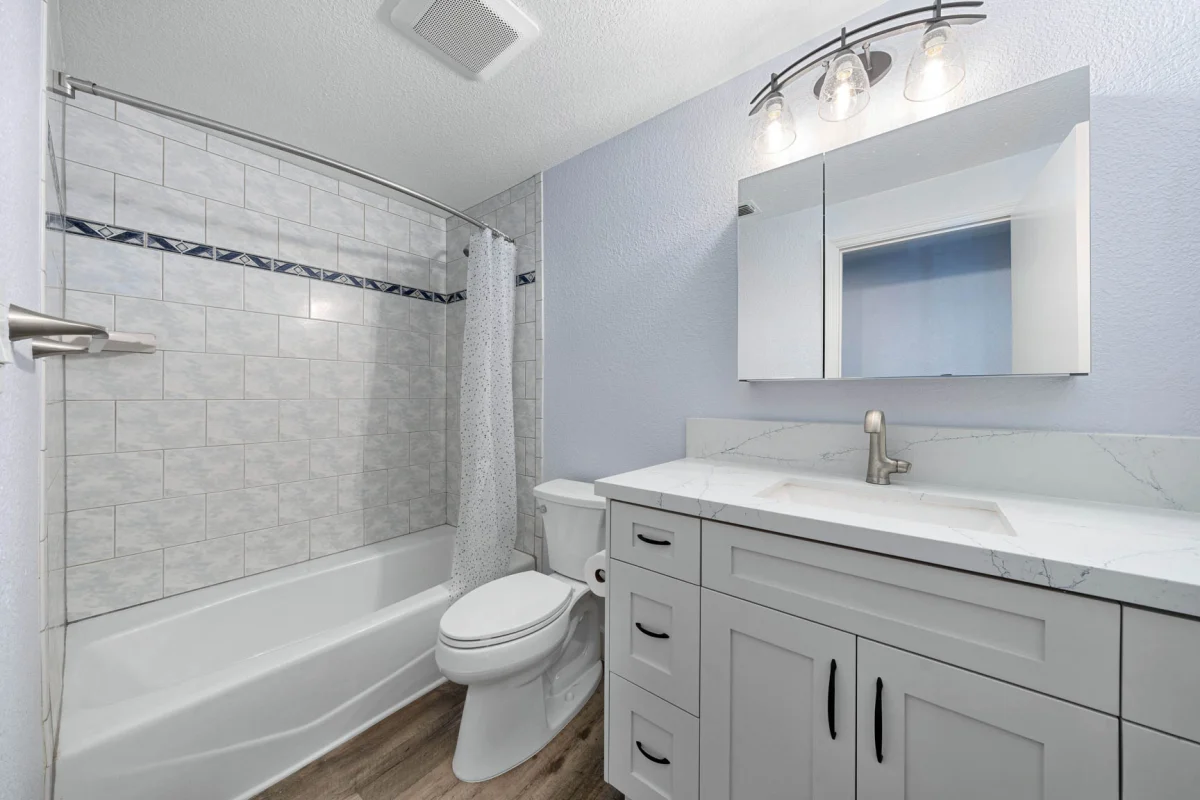 Bathroom with a gray vanity and a tiled tub surround