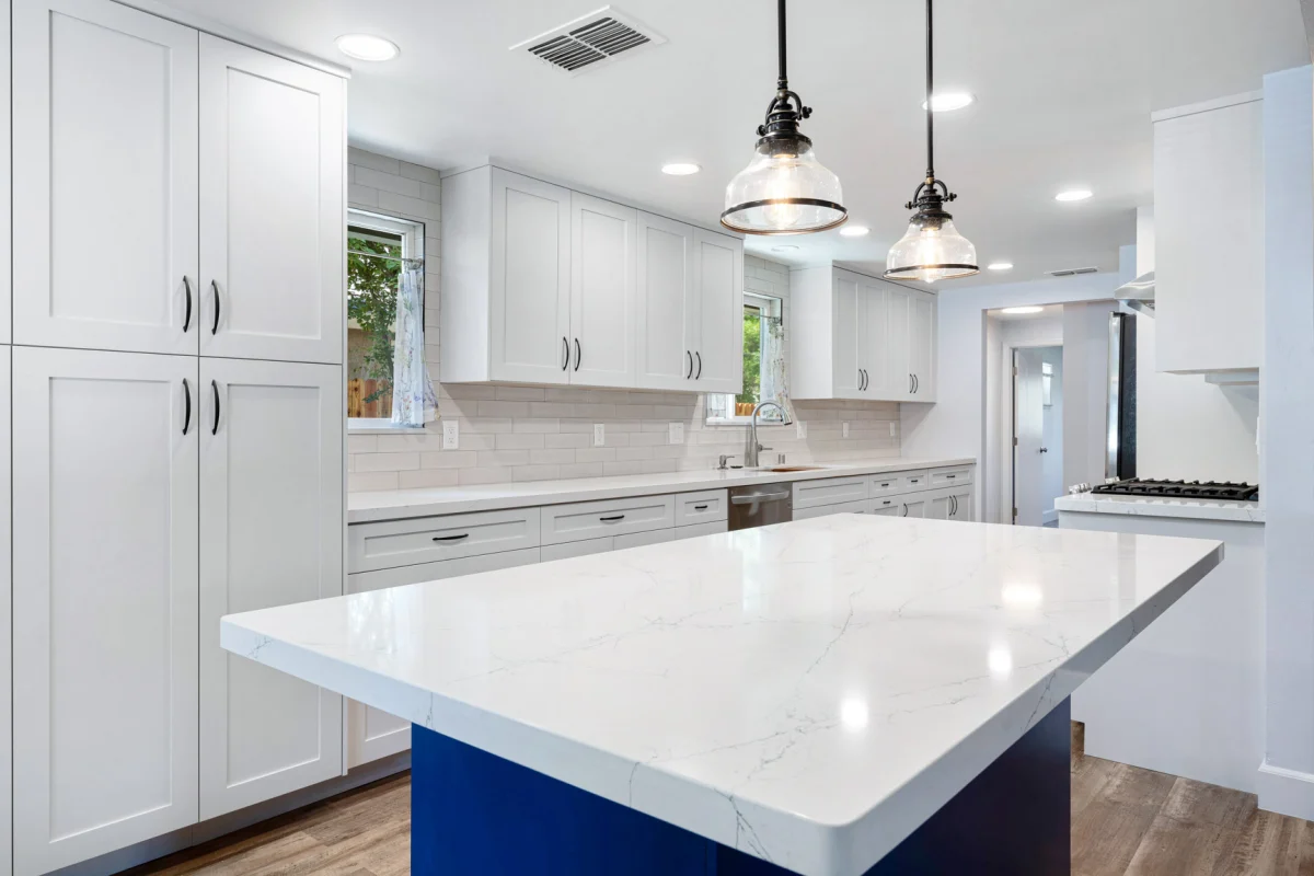 White kitchen with a navy island and glass pendant lights