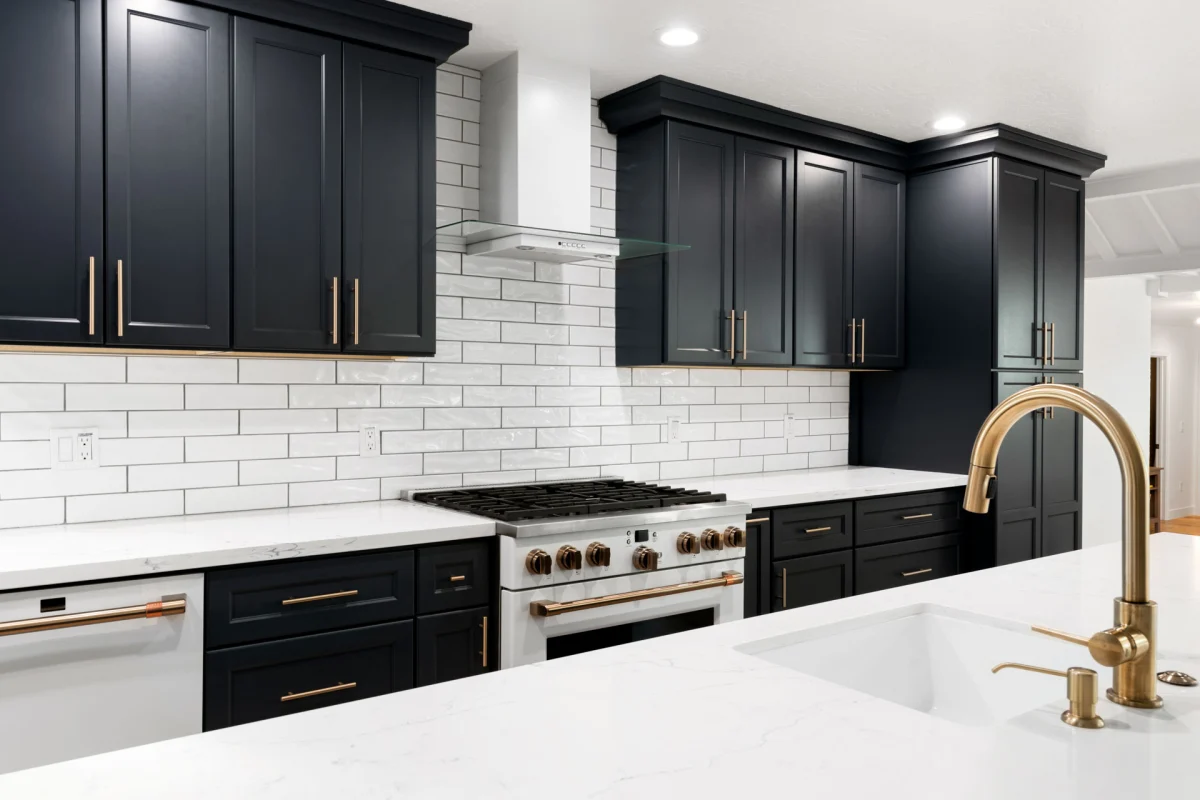 Kitchen with navy cabinets, white subway tile and a brass faucet