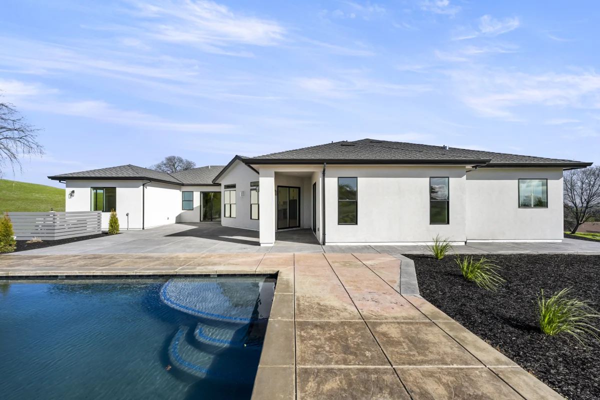 Concrete pool deck and walkway leading to the back of a Solid-built home