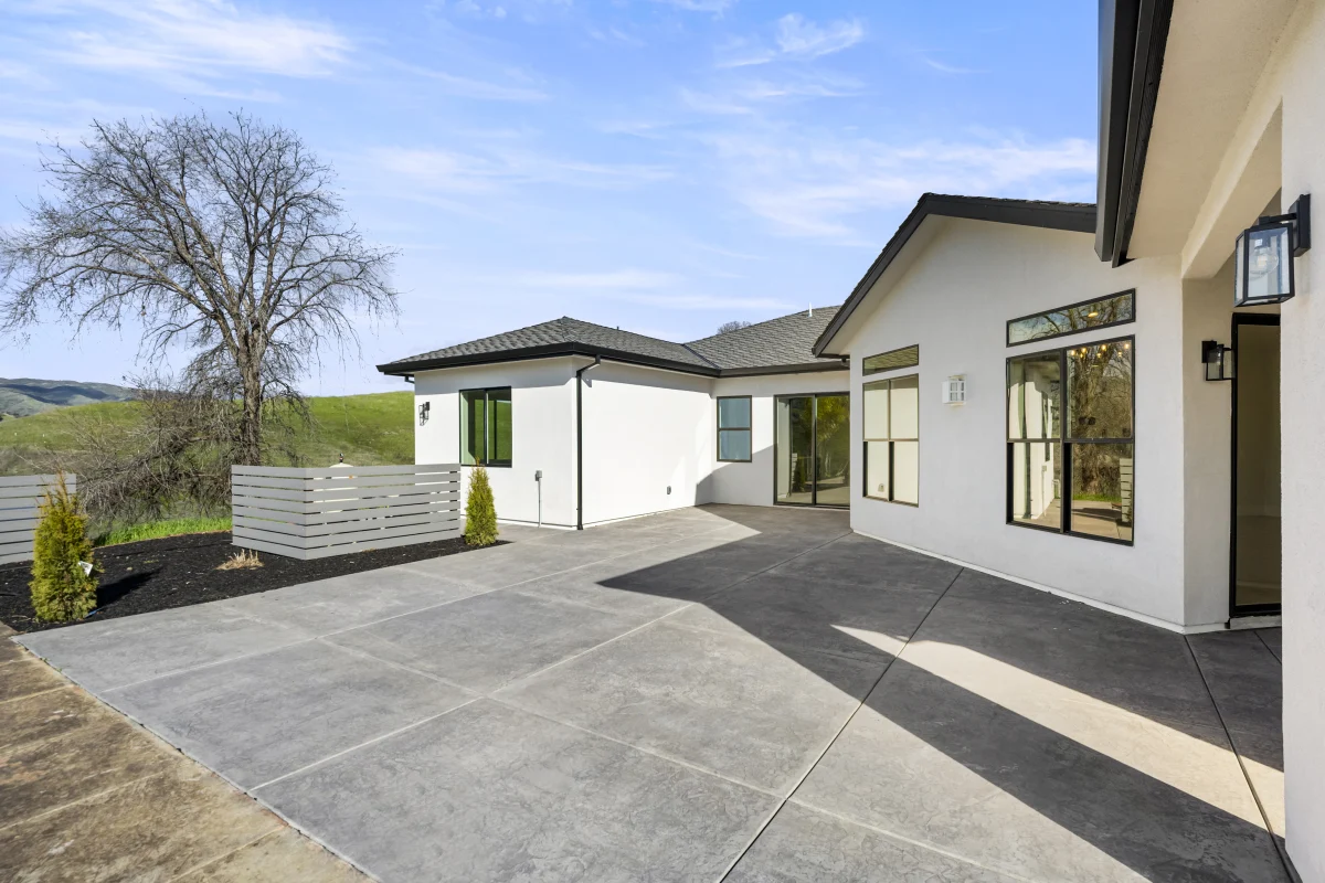 Grey scored concrete patio along the back of a Solid-built home