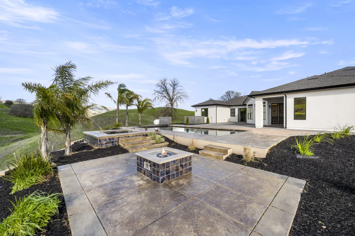 Stained concrete pad with a fire pit beside a pool