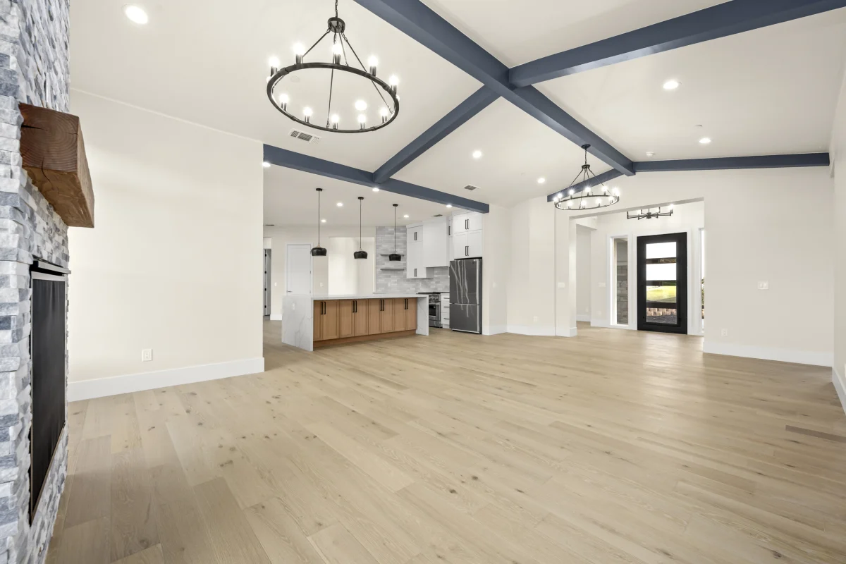 Open great room with a beamed ceiling and kitchen beyond