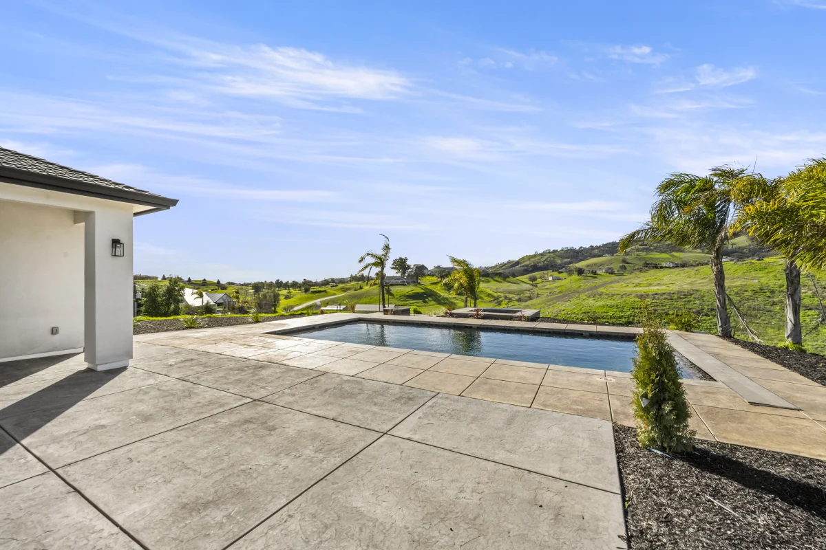 Concrete pool deck with scored joints beside a rectangular pool
