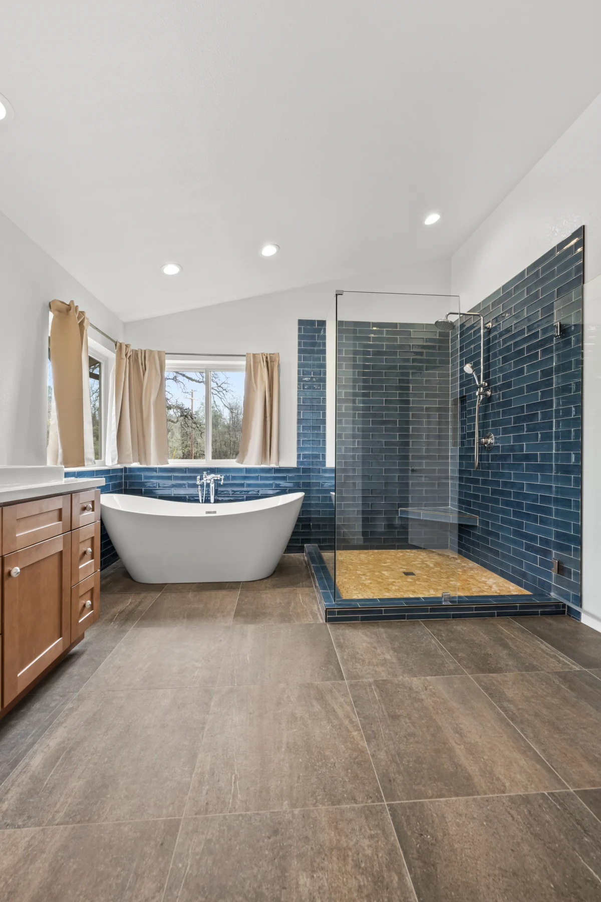 Bathroom with a freestanding tub and blue tile shower