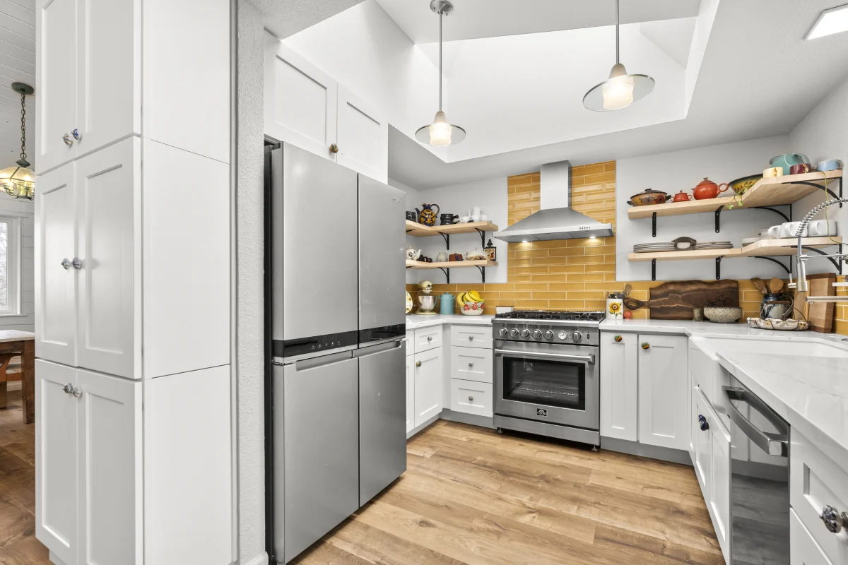 Kitchen with white cabinets, open shelves and a yellow tile backsplash