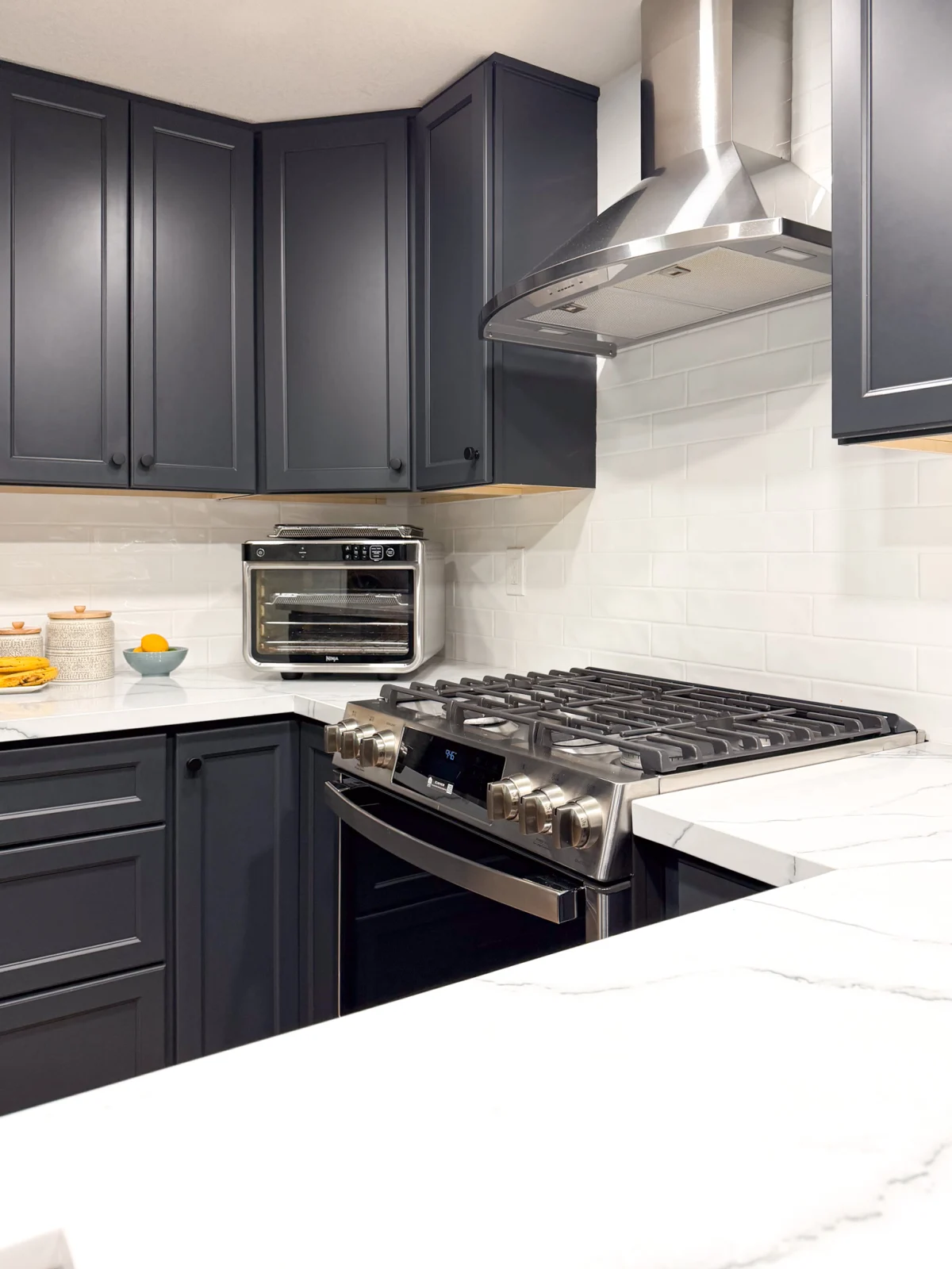 Kitchen with dark gray cabinets and a range hood