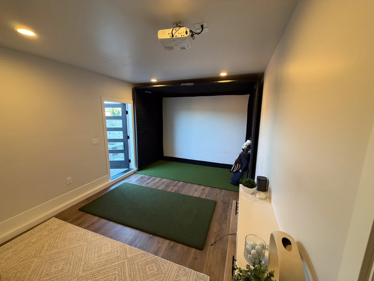 Basement golf simulator room with a projection screen