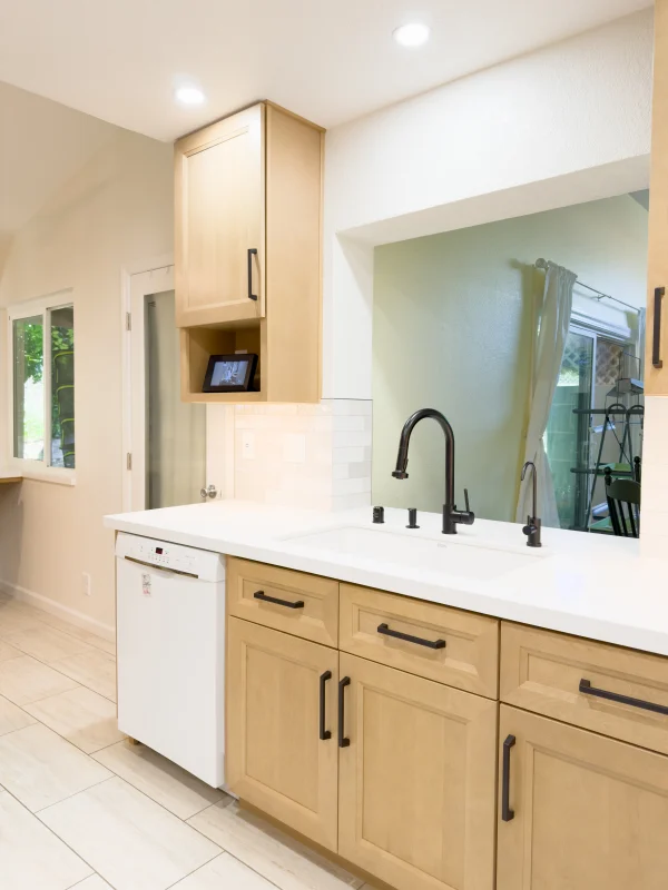 Kitchen sink with light wood cabinets and a black faucet