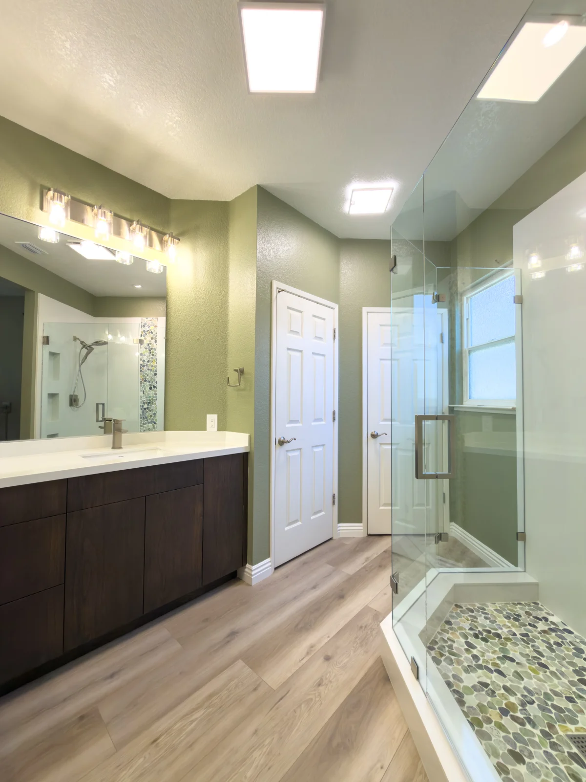 Bathroom with a dark vanity, green walls and a glass shower