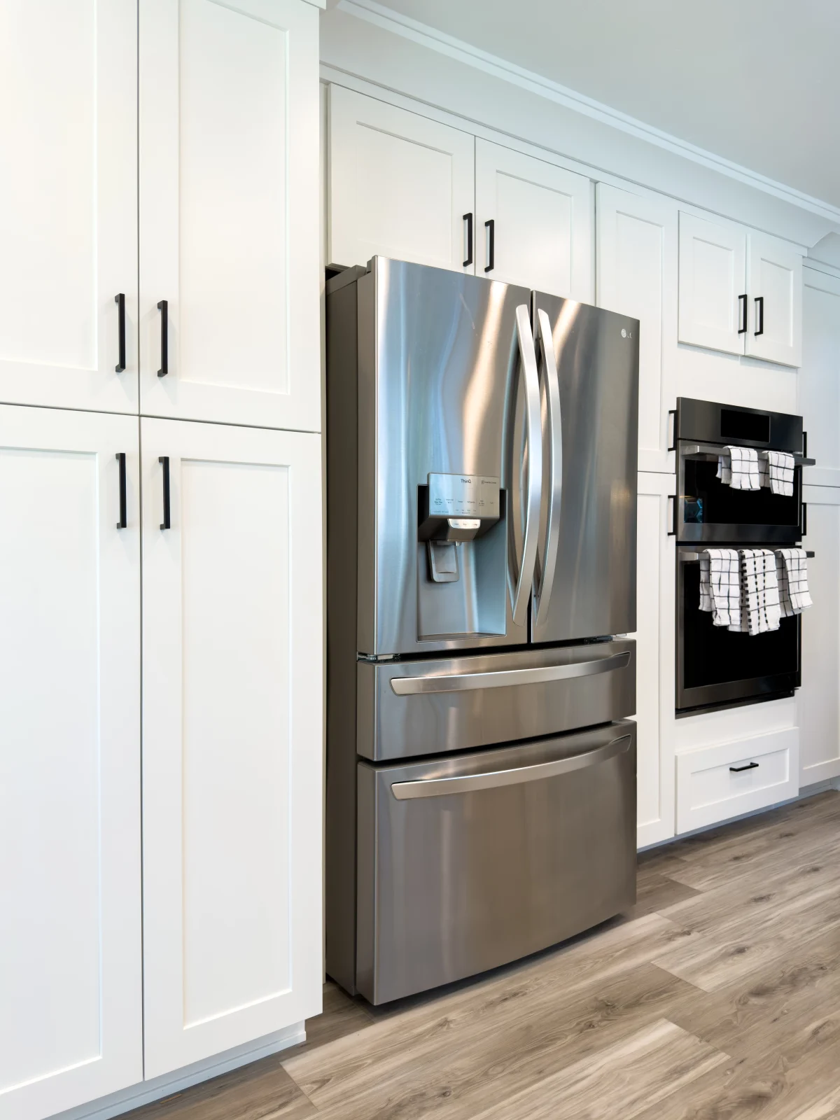 White cabinets around a stainless fridge and wall oven