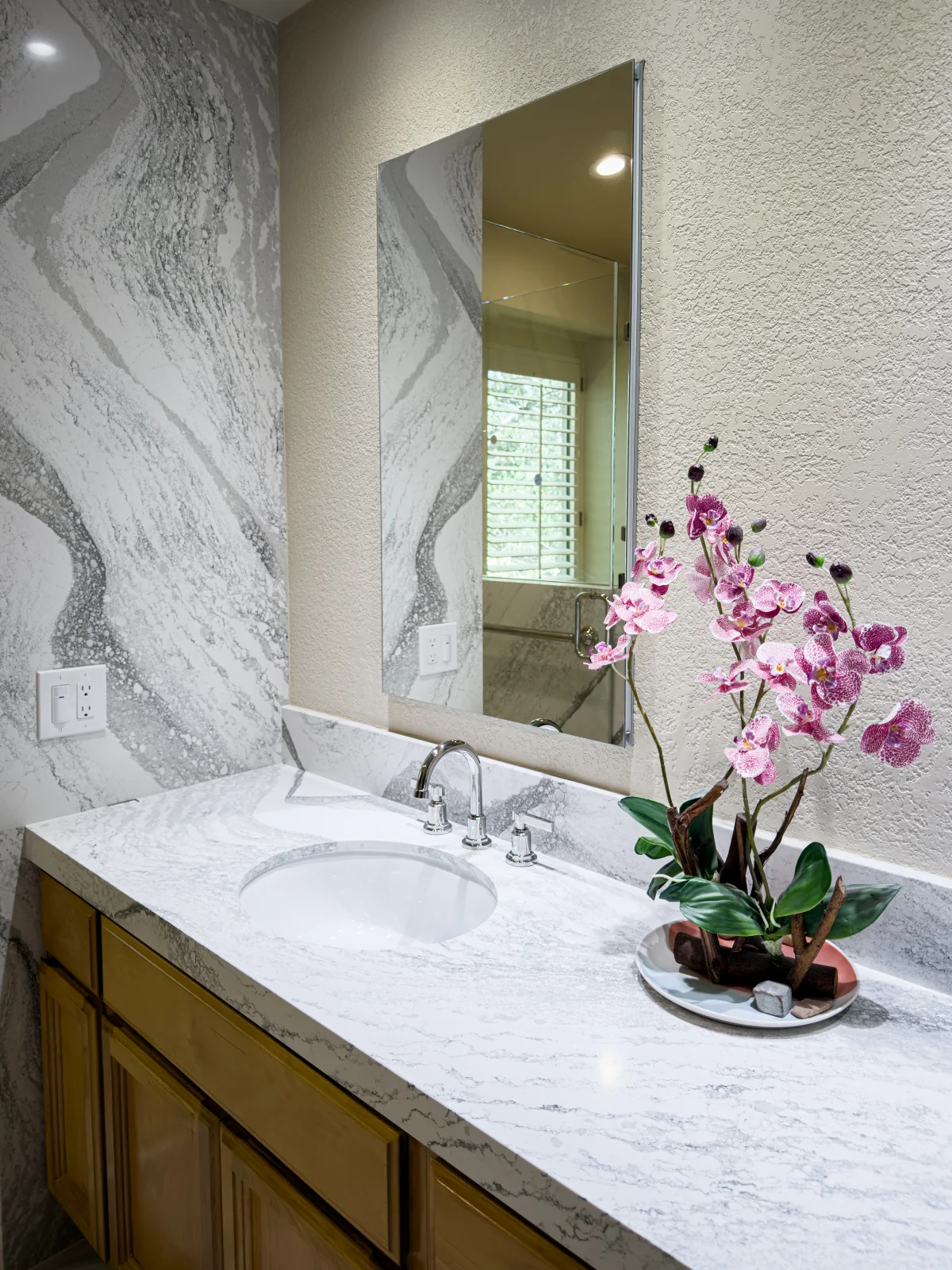 Bathroom vanity with a marble-look counter and an orchid
