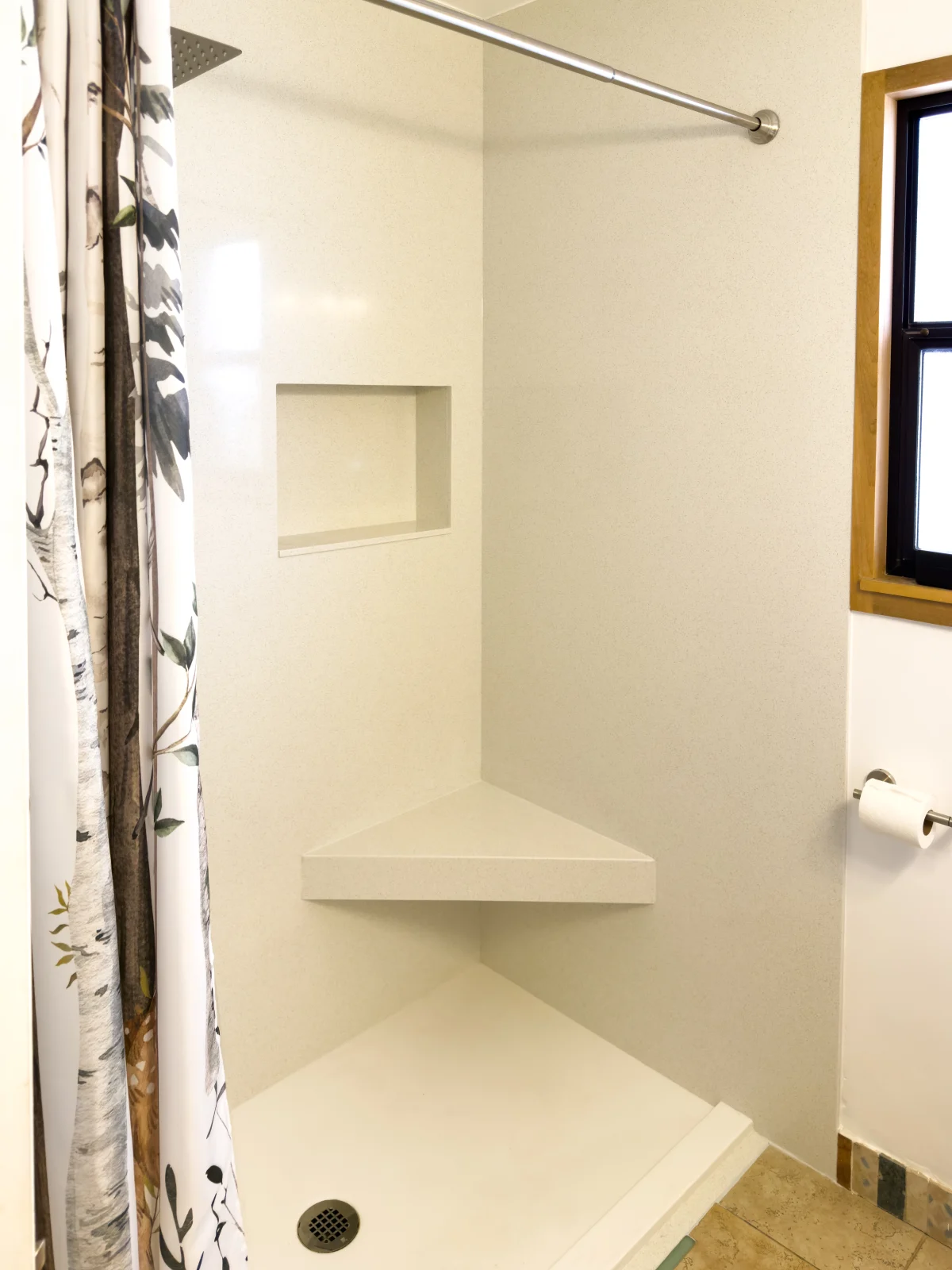 White walk-in shower with a corner seat and a niche