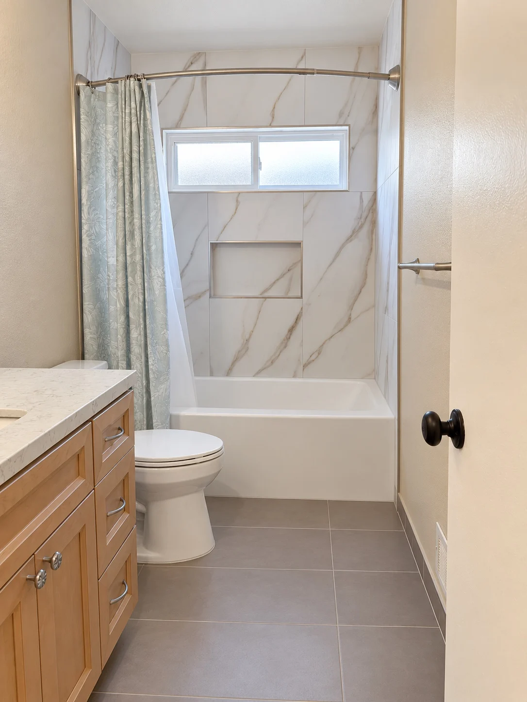 Bathroom with a wood vanity and a marble-look tub surround