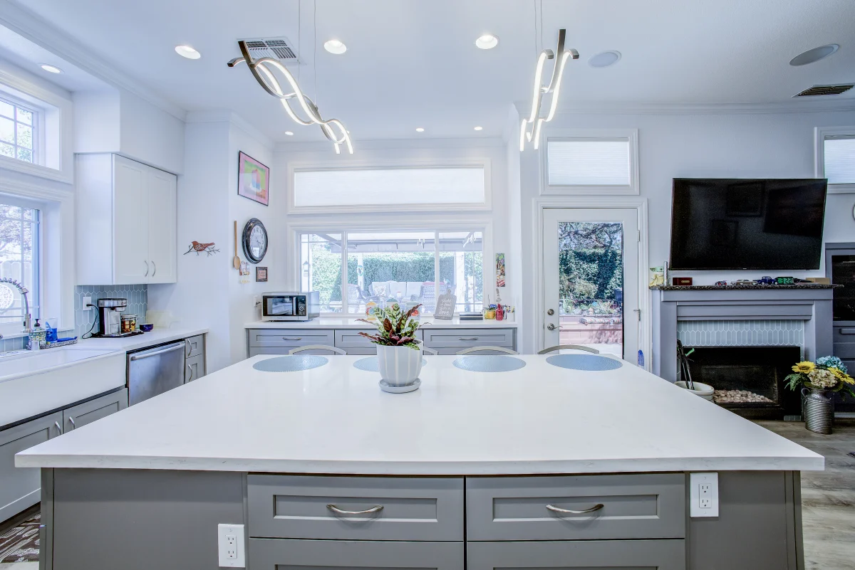 Kitchen with a gray island, white counters and modern light fixtures