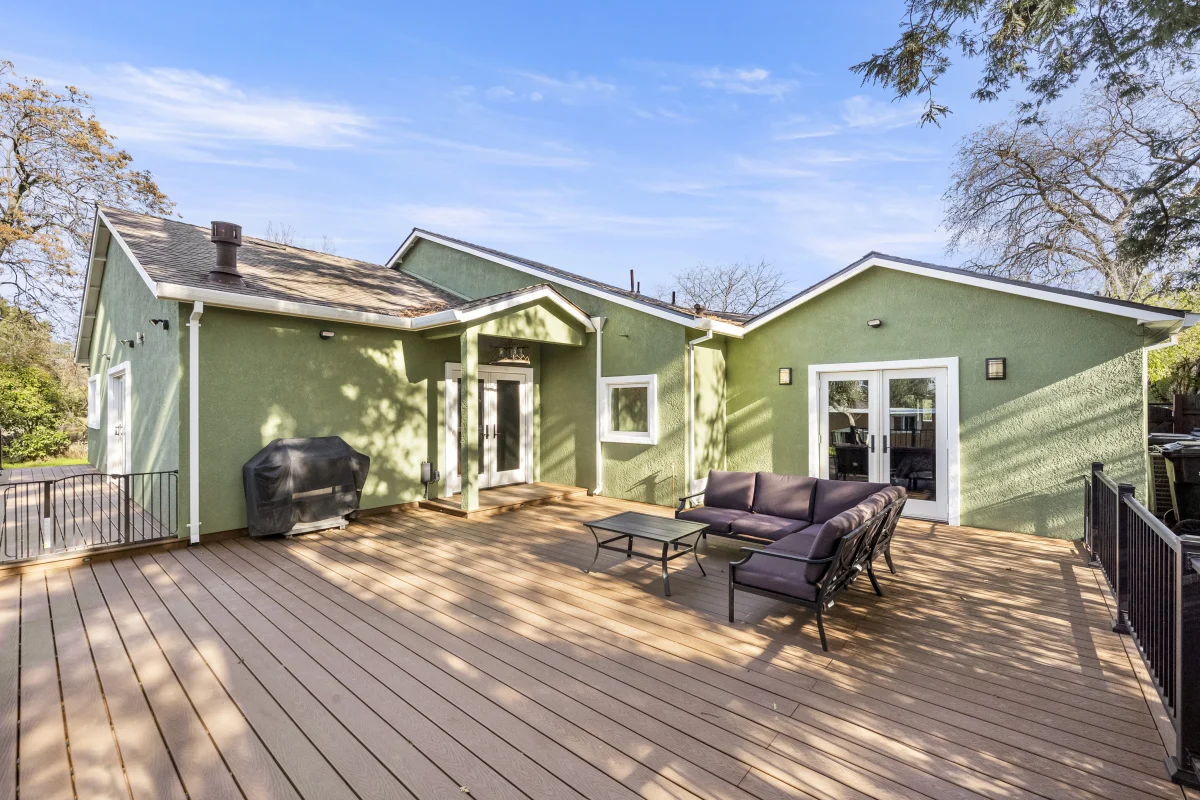 Green house with a large wood deck and seating