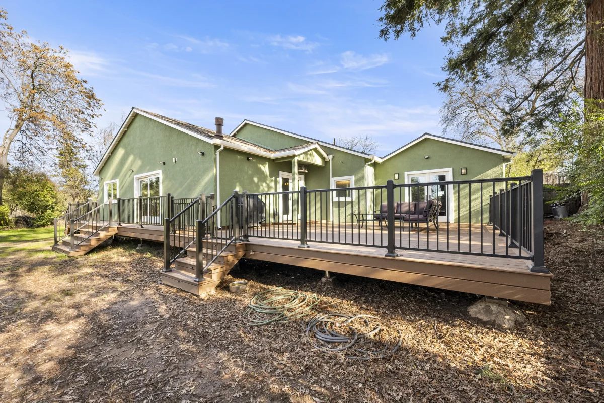 Green house with a new wood deck and black railing
