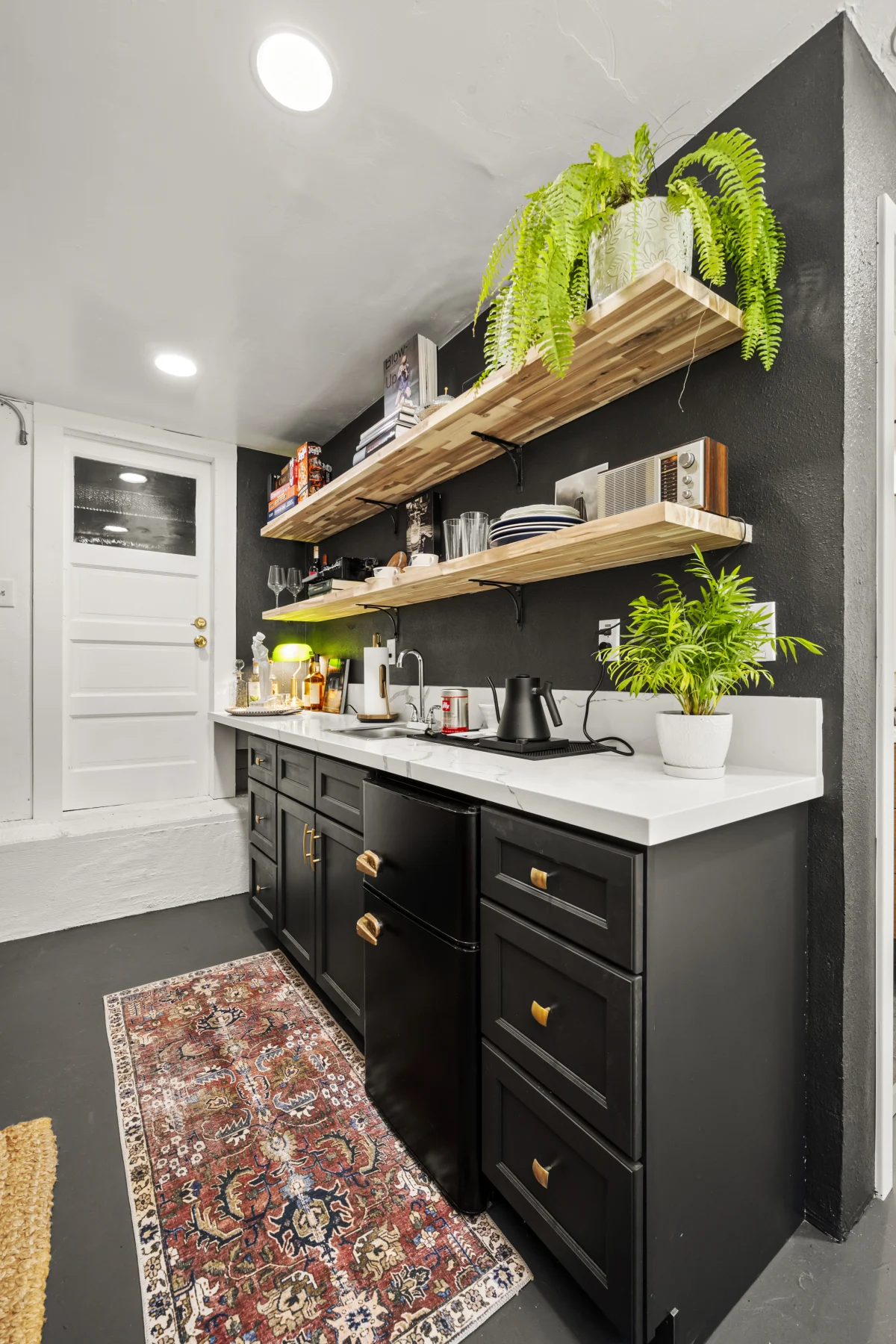 Kitchenette with black cabinets and open wood shelves