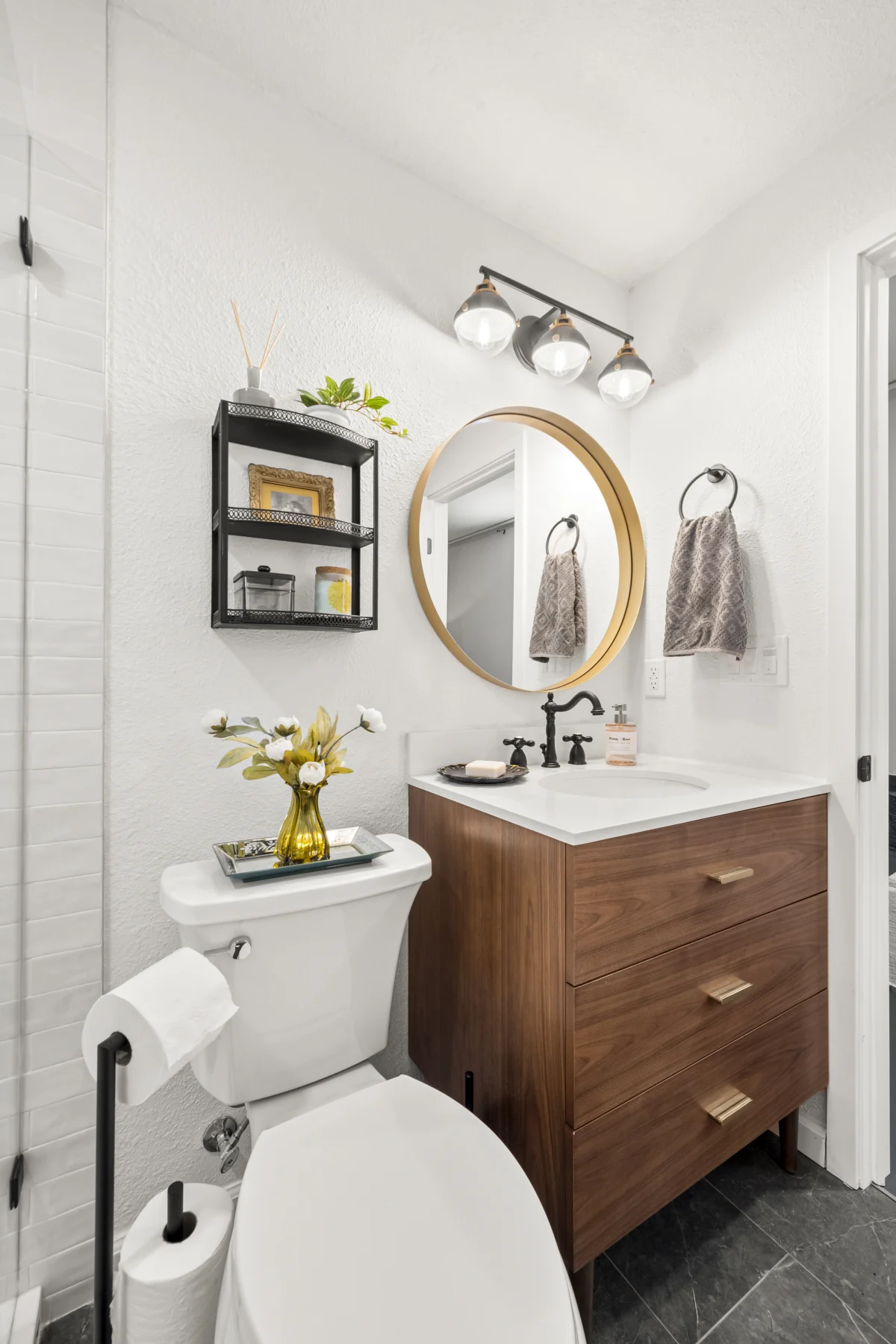 Small bathroom with a wood vanity and round mirror