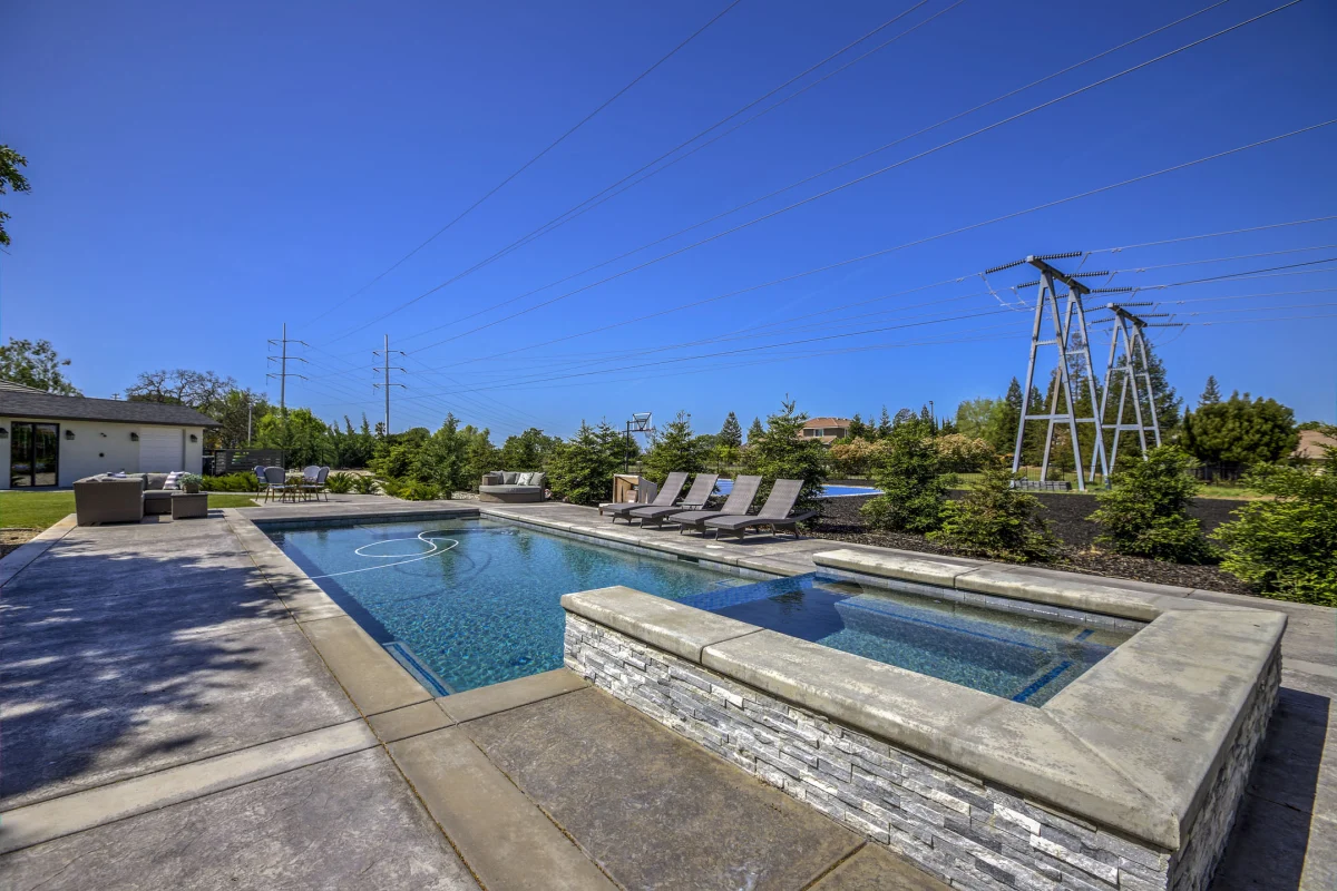 Backyard pool and spa with lounge chairs