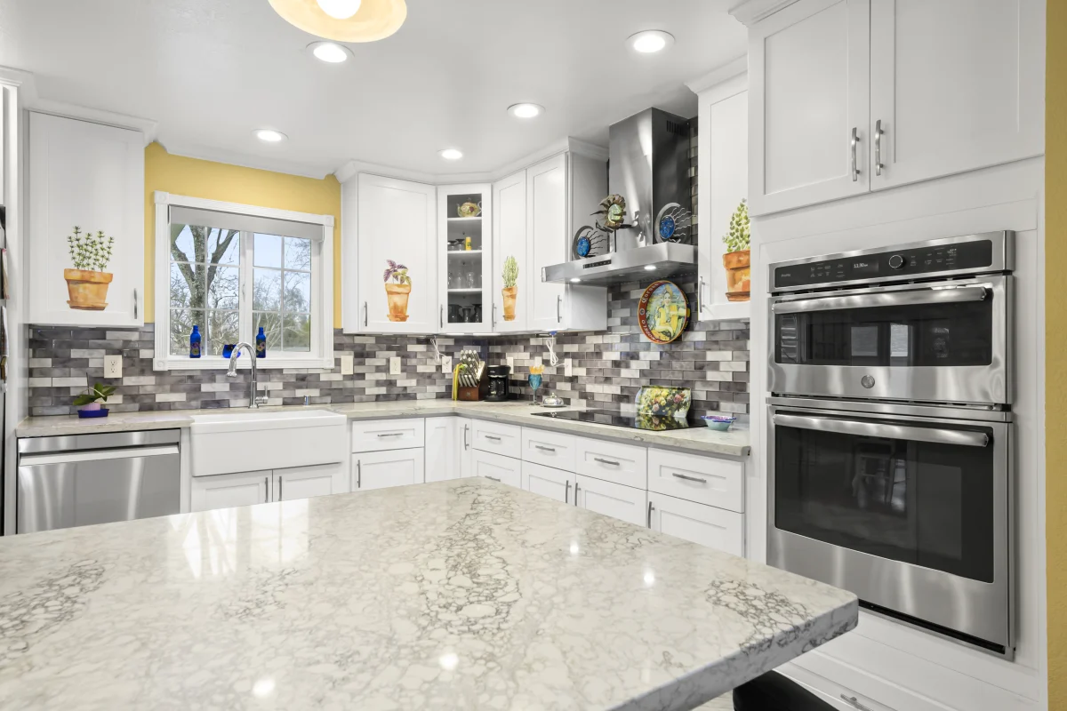 White kitchen with a gray granite counter and a mosaic backsplash