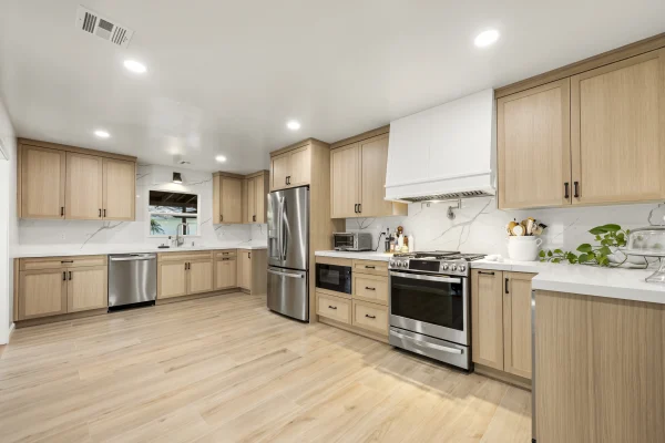 Kitchen with light oak cabinets, white counters and a white range hood