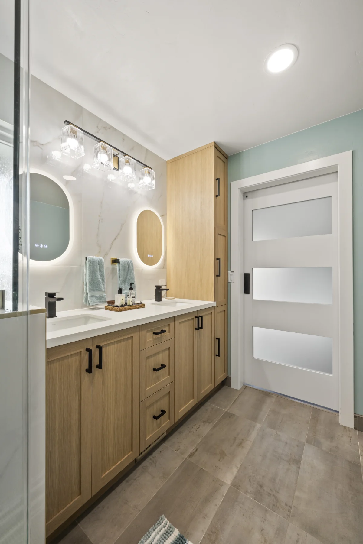 Bathroom with a wood vanity and lit mirrors