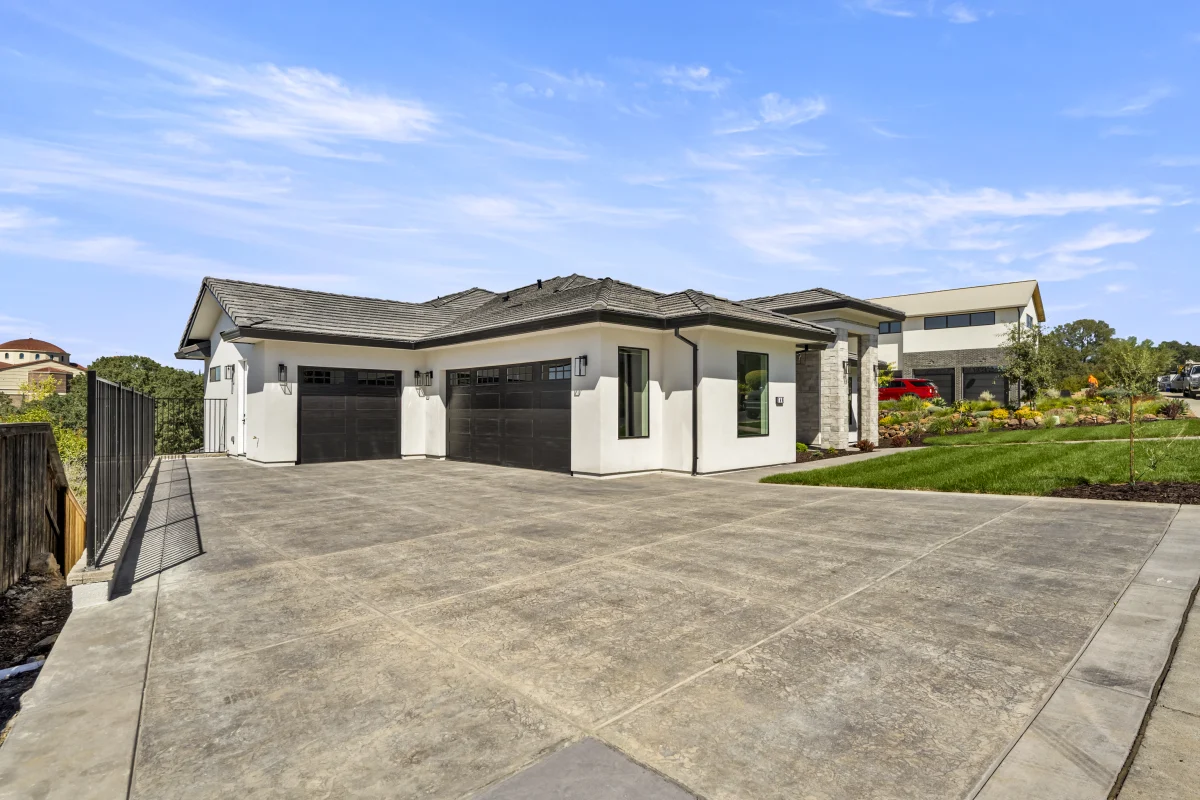 Wide scored concrete driveway in front of the garages of a Solid-built home