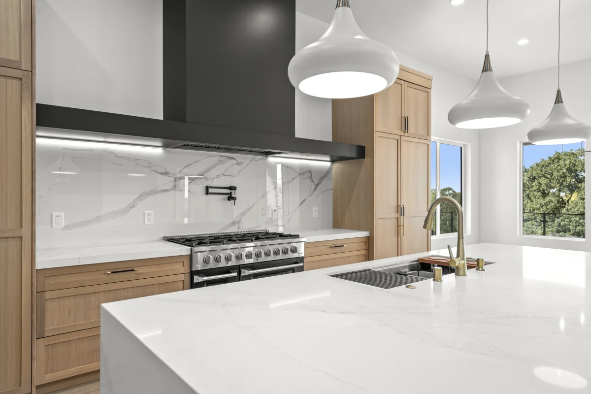 Custom kitchen remodel by Solid Construction & Design with white oak cabinetry, a marble waterfall island and a professional range