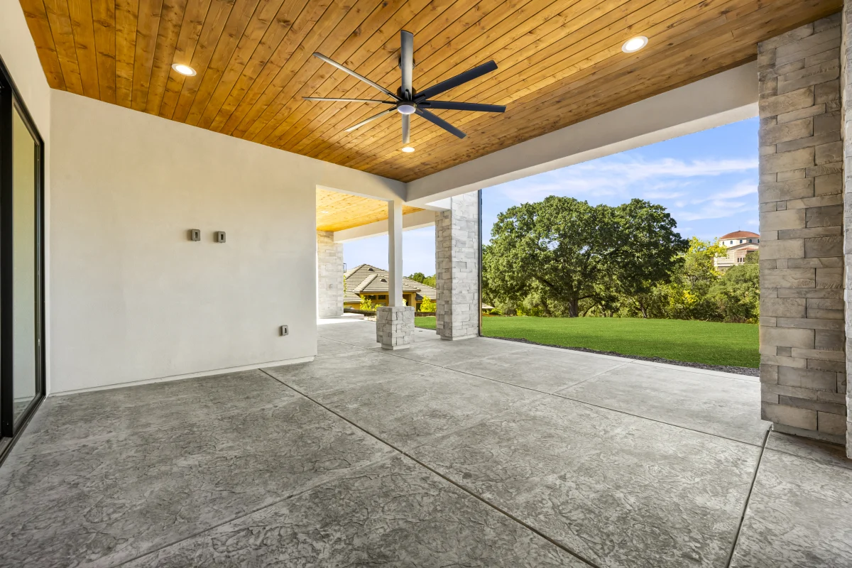 Solid patio cover with a ceiling fan and stone columns, built off the back of a Solid custom home