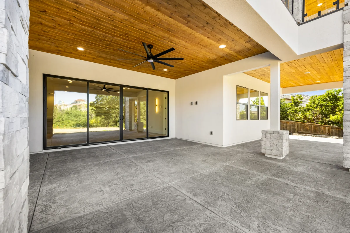 Covered patio with a ceiling fan, a cedar-plank ceiling and sliding doors opening into the house