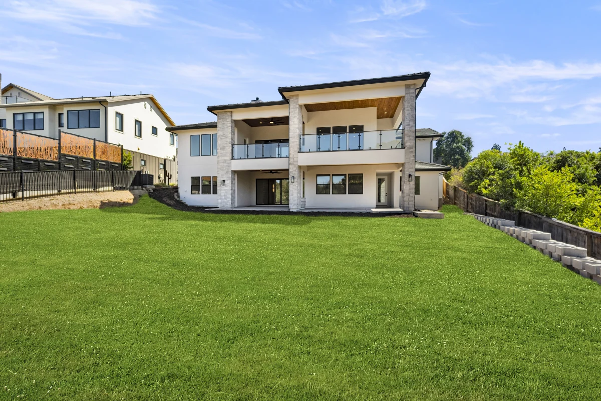 Two-story house with a wide lawn and hillside views
