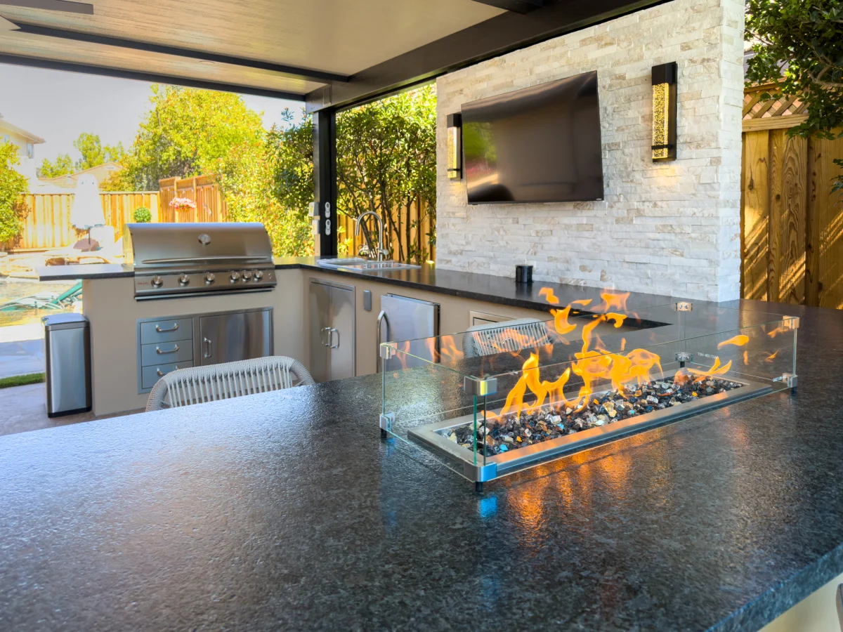 Outdoor kitchen with a fire feature and a TV